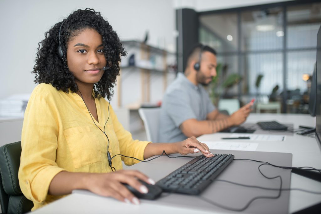 Image showing a woman working as a customer support agent and her colleague in the background.